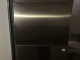 a stainless steel dishwasher in a kitchen with pots and pans on top