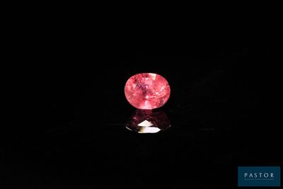 a close up of a pink diamond on a black surface