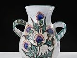 a white vase with blue flowers on it on a table