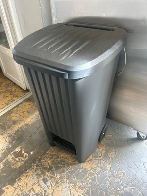 une poubelle grise posée par terre à côté d'une porte