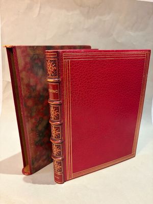 un vieux livre à la couverture rouge posé sur une surface blanche
