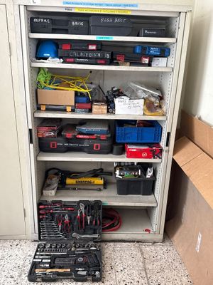une armoire contenant de nombreux outils et une boîte posée par terre