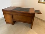 a wooden desk with a glass top and a mirror on the wall