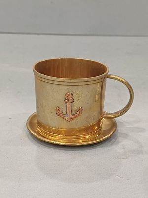 une tasse et une soucoupe en or ornées d'une ancre