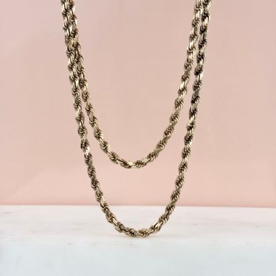 a close up of a gold chain necklace on a pink background