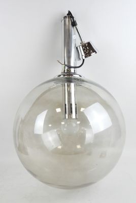 a clear glass vase with a metal handle on a white surface
