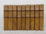 six old books are lined up on a white surface