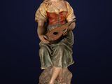 a statue of a woman sitting on a rock holding a guitar