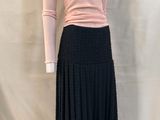 jupe plissée noire avec un pull à col roulé rose