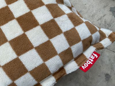 un coussin à carreaux marron et blancs posé par terre
