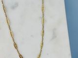 un gros plan d'un collier en or posé sur une surface en marbre