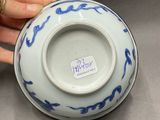 a person holding a blue and white bowl with a sticker on it