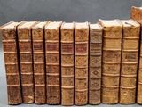 several old books are lined up in a row on a table