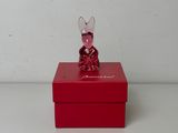 une petite boîte rouge sur laquelle est posée une figurine de souris en verre