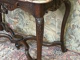 une petite table au plateau en marbre, placée devant un mur recouvert d'un papier peint à motifs floraux