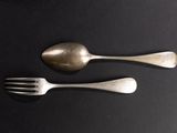 two silver spoons and a fork on a table