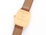 a close up of a watch on a white surface with a brown strap