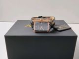 une photo d'une montre posée sur une boîte, elle-même posée sur une table