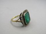 a close up of a ring with a green stone on it
