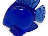 a blue glass fish that is sitting on a white surface