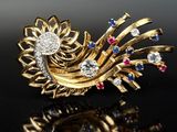 an image of a gold broochle with a flower and colorful stones on it