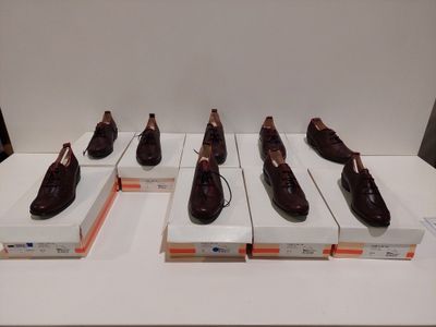 Six paires de chaussures marron sont exposées dans une vitrine.