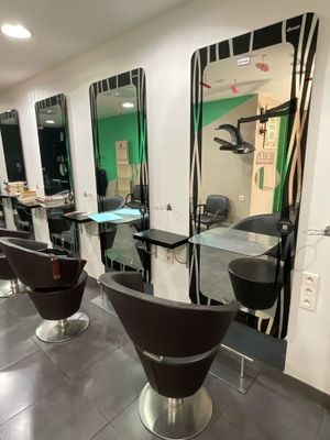 des miroirs accrochés au mur d'un salon de coiffure, avec des fauteuils et une table