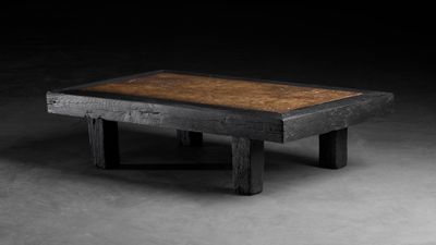 une photo d'une table en bois avec un plateau marron posée sur un sol en béton