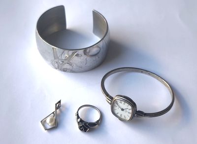 un bracelet, une bague et une montre en argent posés sur une table