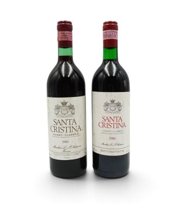 two bottles of red wine sitting next to each other on a white surface