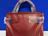 a red leather handbag with clear plastic handles on a table
