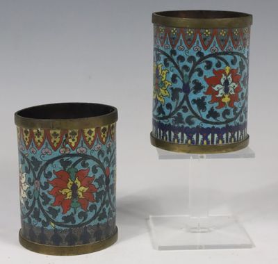 deux petits vases sont posés sur un support, sur une surface blanche