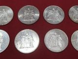 a group of six silver coins sitting on top of a red cloth