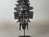 un gros plan d'une sculpture métallique représentant un visage, posée sur un socle