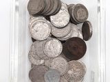 un récipient en verre rempli de pièces de monnaie posé sur une surface blanche