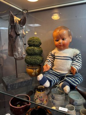 a baby doll sitting on a glass shelf in a display case