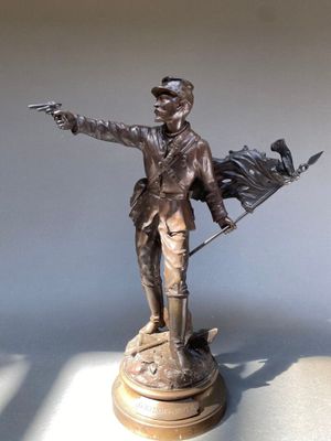 statue en bronze représentant un homme tenant un drapeau et désignant quelque chose du doigt