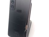 a broken cell phone sitting on a stand on a white surface