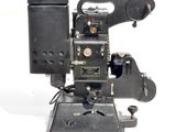 un vieux projecteur de cinéma posé sur une surface blanche