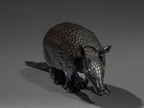 a small statue of an armadile on a gray surface