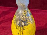 a yellow vase with a design on it sitting on a red cloth