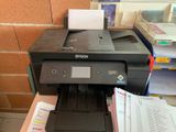 a printer sitting on top of a desk next to a pile of papers