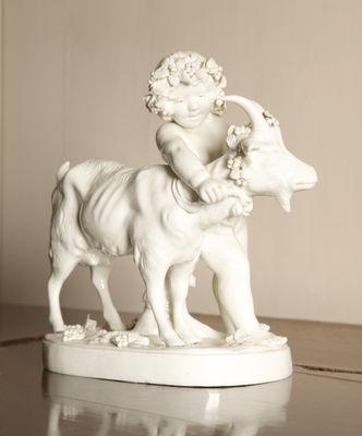 a statue of a child riding a goat on a table