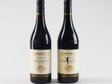 two bottles of wine sitting next to each other on a white surface