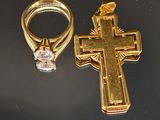 une croix en or et une bague en diamant posées sur une table