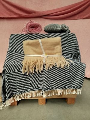 a black and white blanket on a wooden stand next to a pink blanket