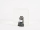a black rock in a clear glass container on a white surface
