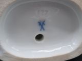 une figurine ancienne en porcelaine représentant un homme, sur laquelle figure une croix