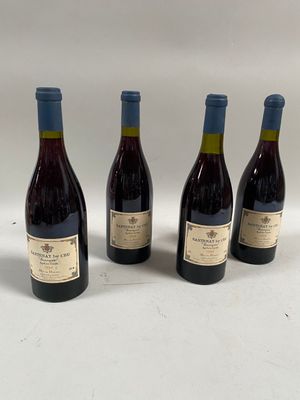 quatre bouteilles de vin sont alignées sur une surface blanche