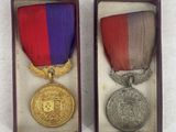 two medals are sitting in a box on a white surface